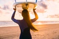 Surf girl with long hair go to surfing. Woman with surfboard on a beach at sunset or sunrise. Surfer and ocean