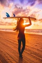 Surf girl with long hair go to surfing. Young woman with surfboard on a beach at sunset.