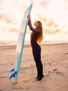 Surf girl with long hair and surfboard on a beach at sunset or sunrise. Surfer and ocean Royalty Free Stock Photo