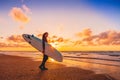 Surf girl with longboard go to surfing. Woman with surfboard on a beach at sunset.