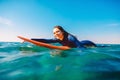 Surf girl is smiling and rowing on the surfboard. Woman with surfboard in ocean. Surfer and ocean