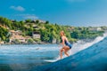Surf girl at surfboard on blue wave in Bali. Caucasian woman during surfing