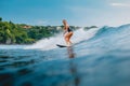 Surf girl at surfboard on blue wave in Bali, Impossibles beach. Sporty woman during surfing