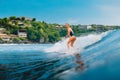 Surf girl at surfboard on blue wave in Bali, Impossibles beach. Sporty woman during surfing