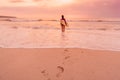 Surf girl with surfboard go to surfing. Surfer woman on a beach at sunset or sunrise.