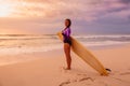 Surf girl with surfboard poising on a beach at sunset or sunrise. Royalty Free Stock Photo