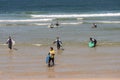 surf lessons. A group of young boys and girls in white t-shirts come out of the sea with the instructor in front Royalty Free Stock Photo