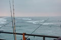 Fishing poles hang over the rail of a pier and over the water. Royalty Free Stock Photo