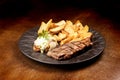 surf and turf - fried fish dish with grilled steak and potatoes at an angle on wooden table Royalty Free Stock Photo