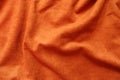 Surface of reddish orange artificial suede fabric in soft folds