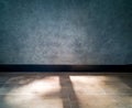 The surface of the cement wall is bare, blue-gray. Black baseboard, brown brick block floor