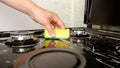 Surface cleaning, woman washing gas stove with yellow washcloth and detergent