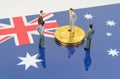 On the surface with the image of the flag of Australia are bitcoins and miniature figurines of people