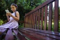 Surface level of girl sitting on wooden bench while using mobile phone Royalty Free Stock Photo