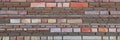 Varicolored flat stones of regular shape in the wall construction. Panorama