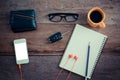 The surface of a wooden table with a notebook, smart-phone, glasses, wallet, car keys, coffee cup. Royalty Free Stock Photo