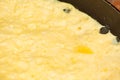 The surface of the yellow homemade omelet in the frying pan