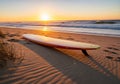 A surfboard rests on a sandy beach during sunrise. The surfboard Royalty Free Stock Photo