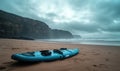Surfboard on sandy beach with dramatic cliffs and overcast sky, surfers in distance, tranquil coastal scene Royalty Free Stock Photo