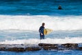 Surfer with blonde hair and yellow board leaving the Atlantic Ocean after enjoying a day of waves on the beach of Las Americas.