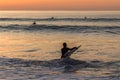 Surfer carrying the surfboard into water with waves in the sunset Royalty Free Stock Photo