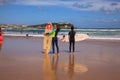 Surfer couple carrying their surfboard on the beach