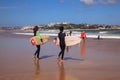 Surfer couple carrying their surfboard on the beach