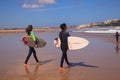 Surfer couple carrying their surfboard on the beach