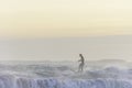 Surfer enjoying evening surf in rough sea at sunset getting splashed by water