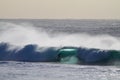 Surfer entering a huge blue barrel in the sea under a clear sky at daytime Royalty Free Stock Photo