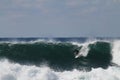 Surfer entering a huge blue barrel in the sea under a clear sky at daytime Royalty Free Stock Photo