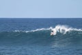 Surfer entering a huge blue barrel in the sea under a clear sky at daytime Royalty Free Stock Photo