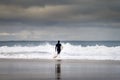 A surfer entering the sea at the Carcavelos Beach in Oeiras