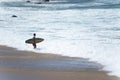 Surfer entering the sea to surf at Farol da Barra beach in the Brazilian city of Salvador Royalty Free Stock Photo