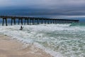 Surfer eyes the moderate sized waves and enters the water to confront them by surfing them just after a rain storm moved past