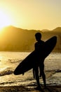 Surfer in front of the sea looking at the waves in front of the city during sunset