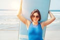 Surfer girl in big sunglasses with long board posing on the ocean beach.Active vacation concept image