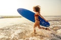 Surfer girl with blue surfboard on the sandy beach. sexy model female bodybuilding and fitness in an orange bikini