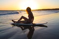 Surfer girl on her board at sunset