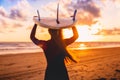 Surfer girl with long hair go to surfing. Woman with surfboard on a beach at sunset or sunrise. Royalty Free Stock Photo