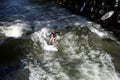 Surfer girl rides the wave that takes shape in the stream of the Englischer Garten or English Garden in Munich.