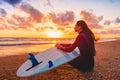 Surfer girl on sand beach with surfboard at warm sunset or sunrise. Royalty Free Stock Photo