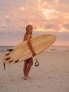 Surfer girl on sand beach with surfboard at warm sunset or sunrise. Attractive surfer on beach Royalty Free Stock Photo