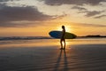 Surfer girl silhouette. Surf woman walking with surfboard on the beach.