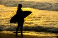 Surfer girl surfing looking at ocean beach sunset. Silhouette w