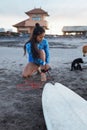 Surfer Girl. Surfing Woman On Sandy Beach With Surfboard And Dog. Asian Female In Blue Wetsuit Going To Surf In Ocean. Royalty Free Stock Photo