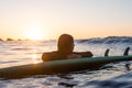 Surfer girl waiting for a wave in the water at sunset Royalty Free Stock Photo