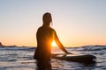 Surfer girl waiting for a wave in the water at sunset Royalty Free Stock Photo