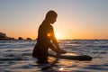 Surfer girl waiting for a wave in the water at sunset Royalty Free Stock Photo