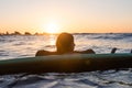 Surfer girl waiting for a wave in the water at sunset Royalty Free Stock Photo
